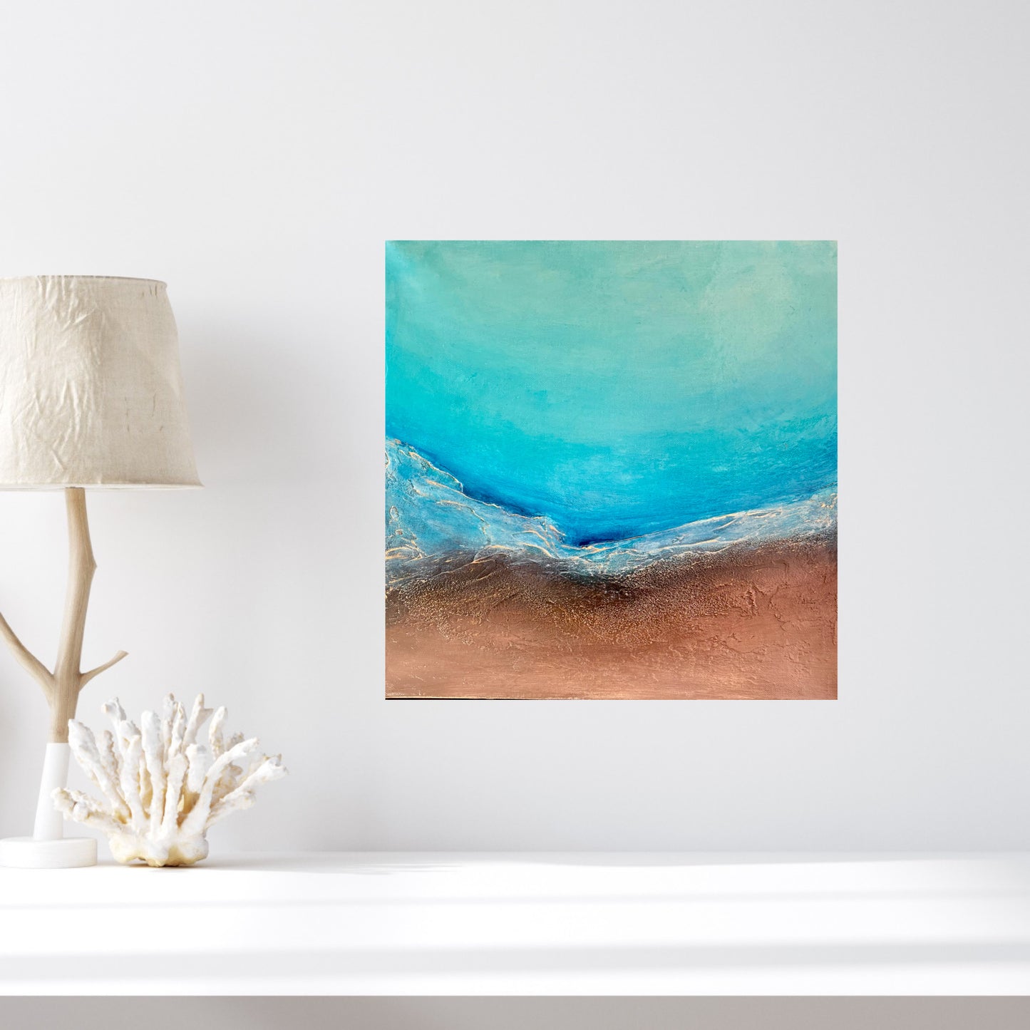 Dance of Water and Earth I mixed media painting by Clémentine Daudier showing turquoise ocean waves meeting sandy beach in contemporary seascape art, in situ on white wall next to a lamp and a coral branch.